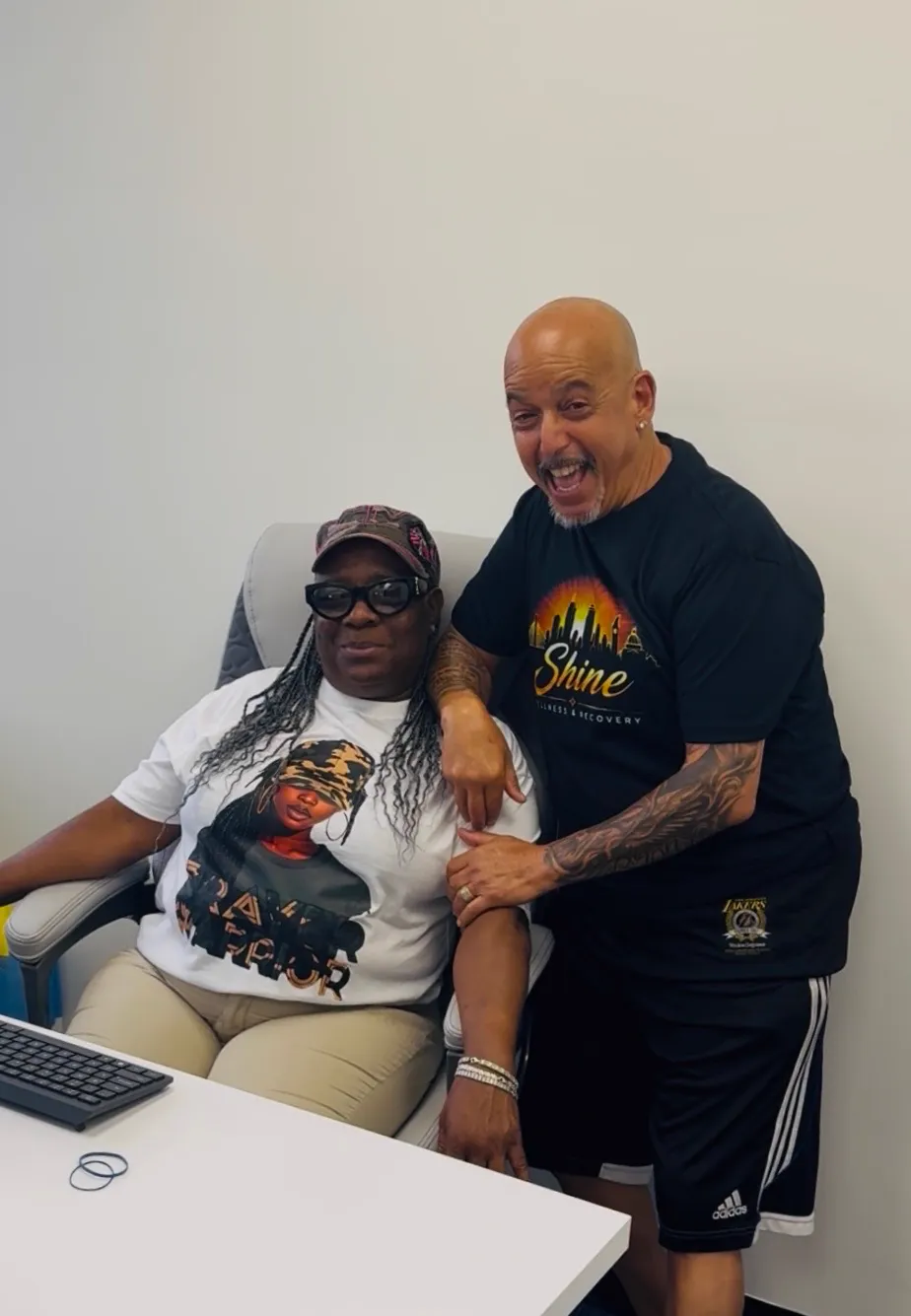 Rob G with a friend wearing a Prayer Warrior shirt at the Shine Wellness office