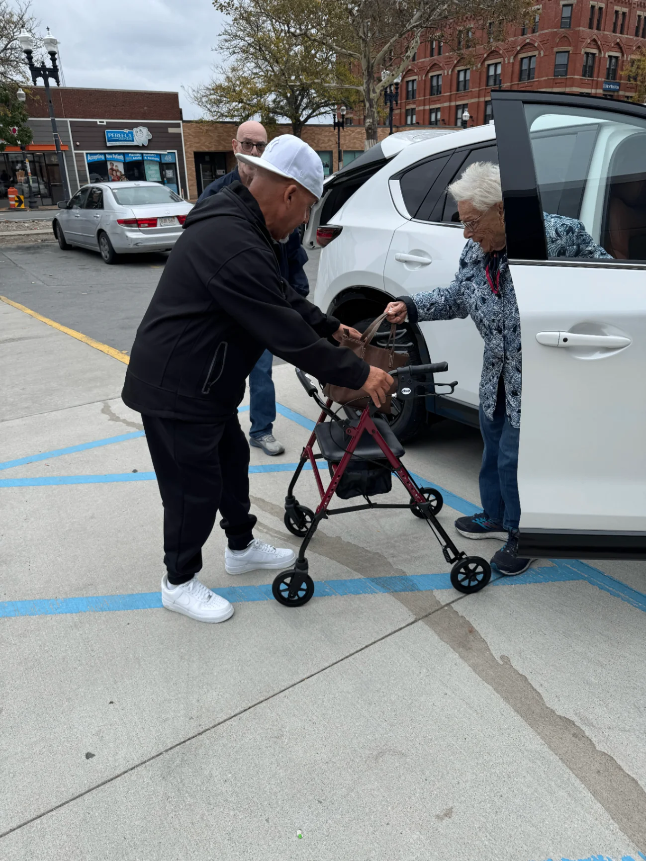Rob G helping an elderly neighbor with a walker at a community event